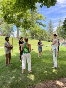 A group stands in the grass while participating in a Capoeira workshop