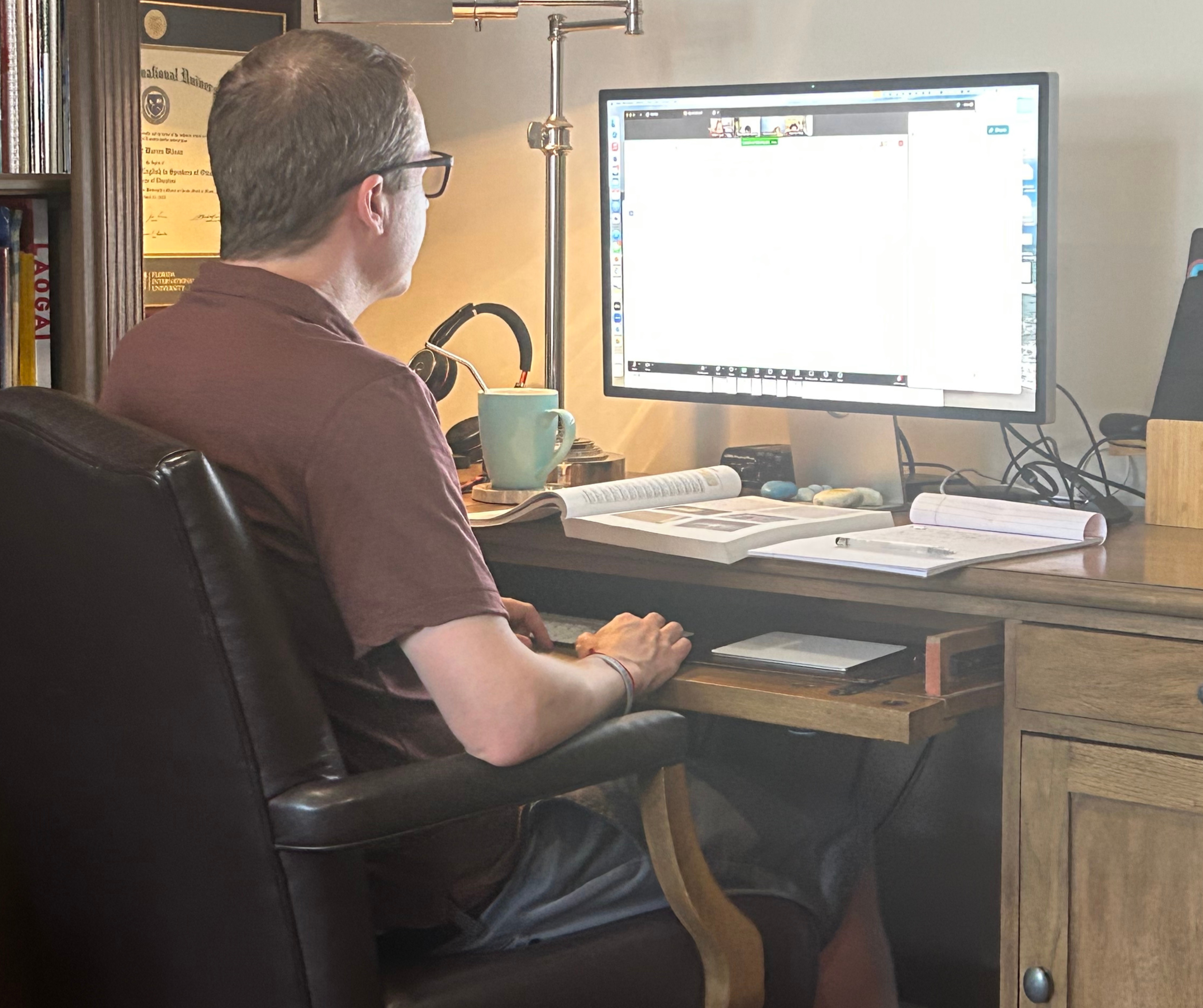 A person sitting in a chair and typing on a computer.