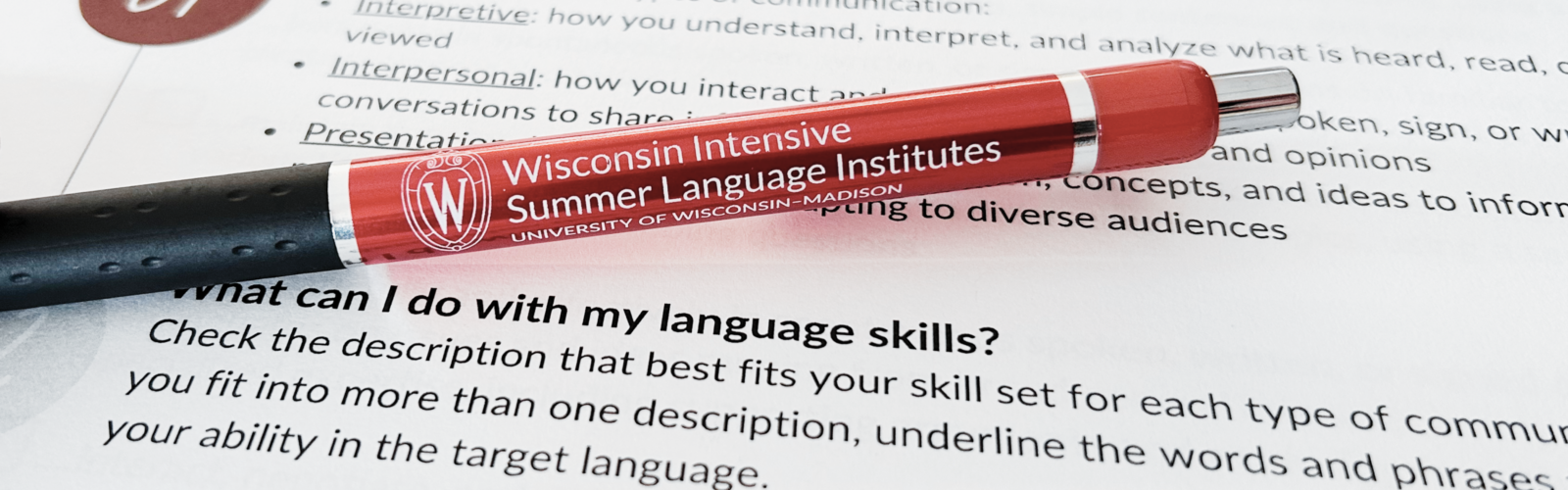 Red Wisconsin Intensive Summer Language Institutes pen resting on a language skills assessment sheet.